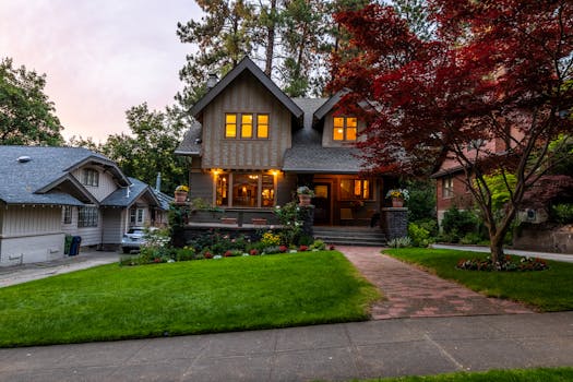 Quaint Victorian-style home with a glowing interior, surrounded by a lush garden at twilight.